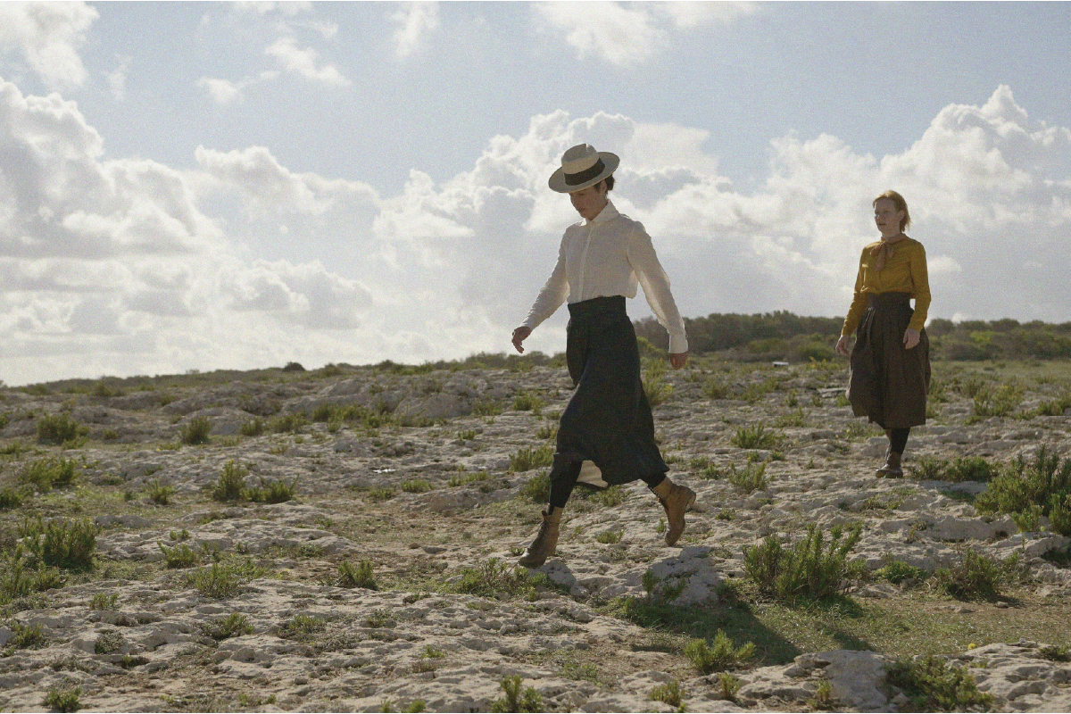 Sissi e Irma camminano in solitudine su un altopiano roccioso, immerse in un paesaggio brullo e battuto dal vento. Una scena simbolica di libertà e distanza dal mondo.