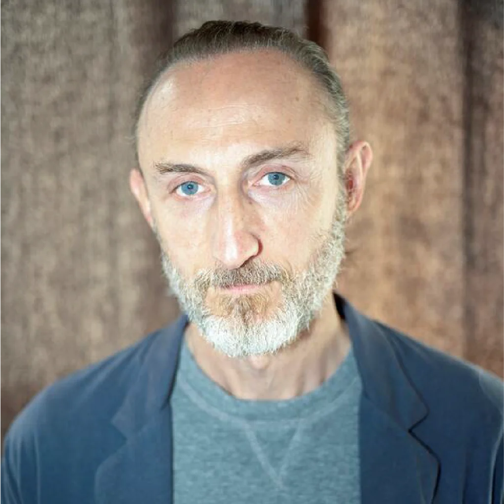 Ritratto del regista Guillaume Nicloux con sguardo intenso e barba brizzolata, autore del film “La Petite”