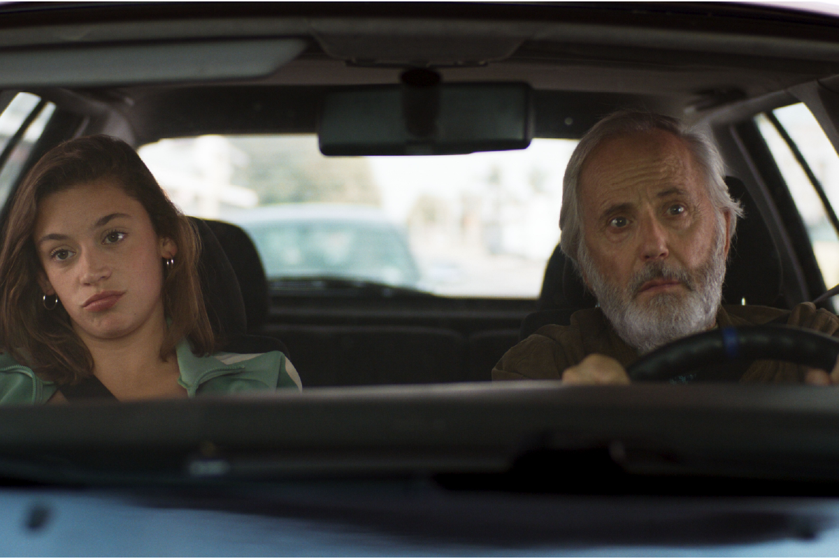 Joseph e Rita viaggiano in auto insieme, con sguardi assorti e silenziosi, durante un momento di transizione del film “La Petite”